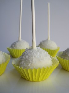 Lemon Cake Pops Lemon cake with cream cheese frosting covered in white chocolate, and topped with sugar crystals.