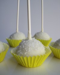 Lemon Cake Pops Lemon cake with cream cheese frosting covered in white chocolate, and topped with sugar crystals.